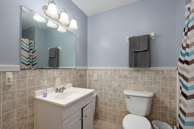 bathroom with tile walls, toilet, vanity, and tile patterned flooring