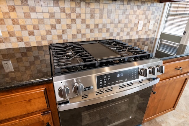 room details with dark stone countertops, stainless steel range with gas stovetop, and backsplash