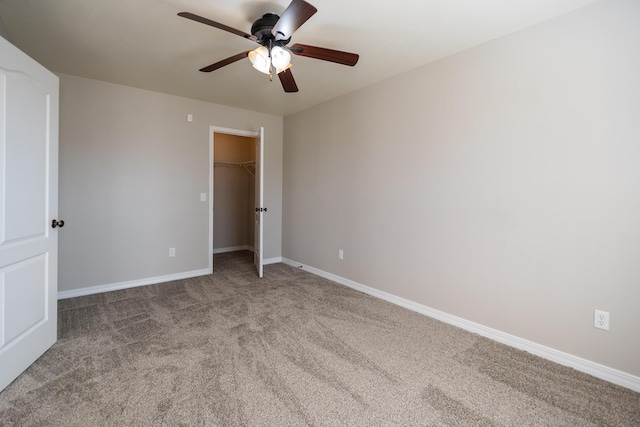 unfurnished bedroom with light carpet, a spacious closet, a closet, and ceiling fan