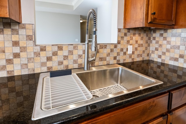 kitchen featuring crown molding, dark stone counters, and backsplash