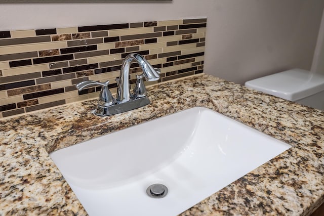 interior details featuring tasteful backsplash, vanity, and toilet