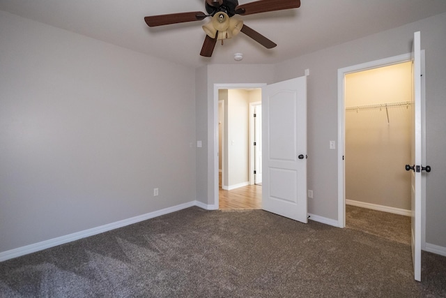 unfurnished bedroom featuring carpet, a spacious closet, ceiling fan, and a closet