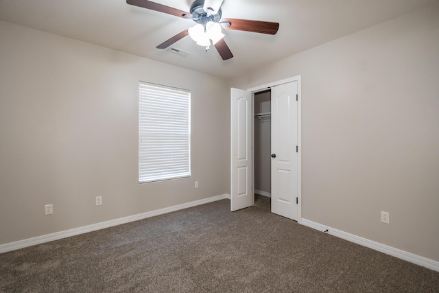 unfurnished bedroom with dark colored carpet, ceiling fan, and a closet