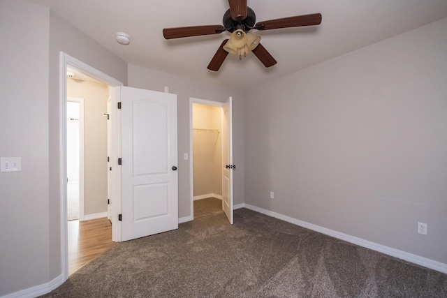 unfurnished bedroom with ceiling fan, a spacious closet, a closet, and carpet flooring