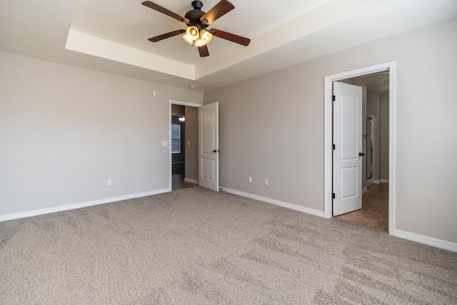 unfurnished bedroom featuring light colored carpet, a raised ceiling, and ceiling fan