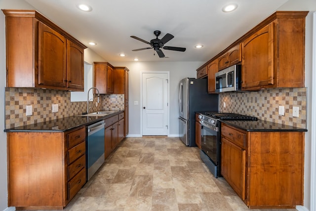 kitchen featuring sink, ceiling fan, appliances with stainless steel finishes, tasteful backsplash, and dark stone counters