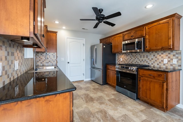 kitchen featuring appliances with stainless steel finishes, sink, dark stone counters, and decorative backsplash