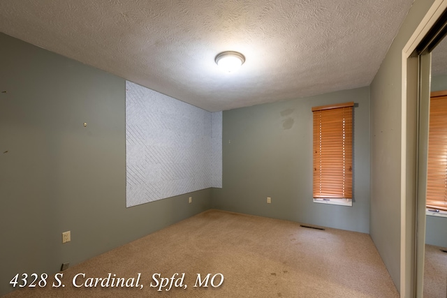 carpeted empty room featuring a textured ceiling