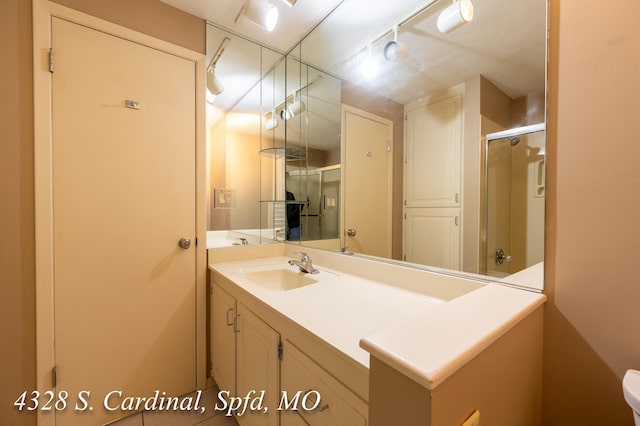 bathroom featuring an enclosed shower, vanity, and track lighting