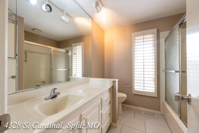 full bathroom featuring a wealth of natural light, toilet, vanity, and tile patterned flooring