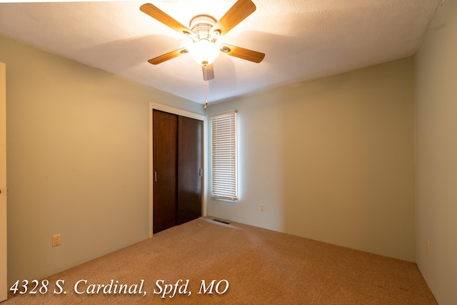 unfurnished bedroom with carpet, a closet, and ceiling fan