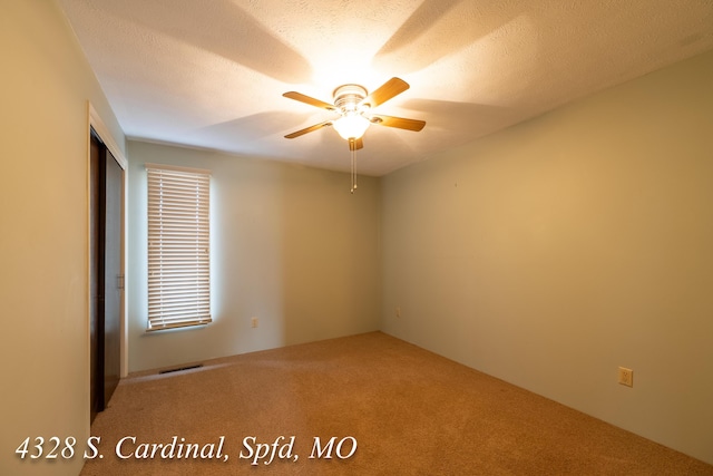 unfurnished room with a textured ceiling, carpet flooring, and ceiling fan