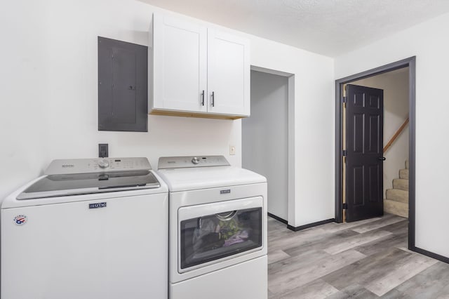 laundry room featuring a textured ceiling, cabinets, independent washer and dryer, light wood-type flooring, and electric panel