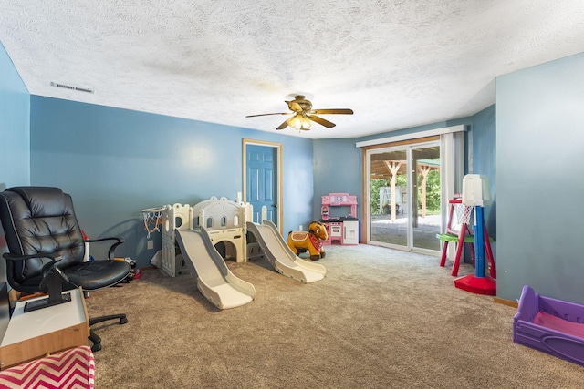 recreation room with a textured ceiling, carpet flooring, and ceiling fan