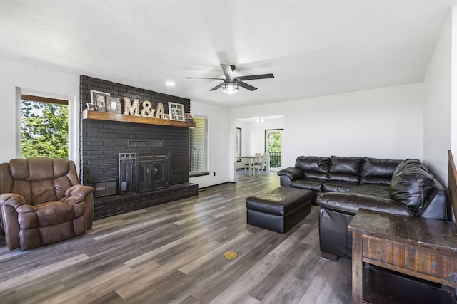 living room with ceiling fan, dark hardwood / wood-style floors, a wealth of natural light, and a brick fireplace