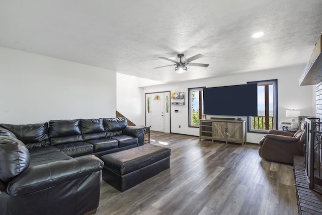 living room featuring ceiling fan, dark wood-type flooring, and a textured ceiling