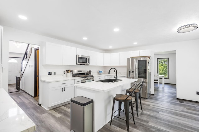 kitchen featuring sink, white cabinets, appliances with stainless steel finishes, and a center island with sink