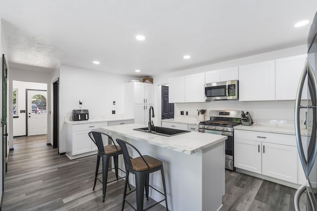 kitchen featuring sink, white cabinets, a kitchen island with sink, and appliances with stainless steel finishes