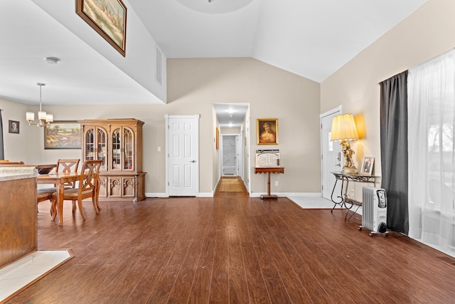 entrance foyer with vaulted ceiling, an inviting chandelier, and dark hardwood / wood-style flooring