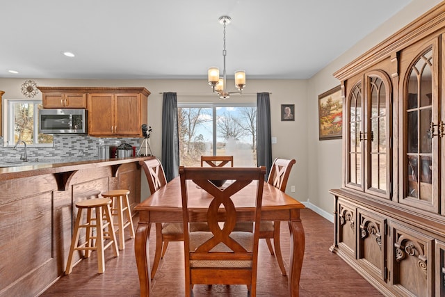 dining space with sink, an inviting chandelier, and dark hardwood / wood-style flooring