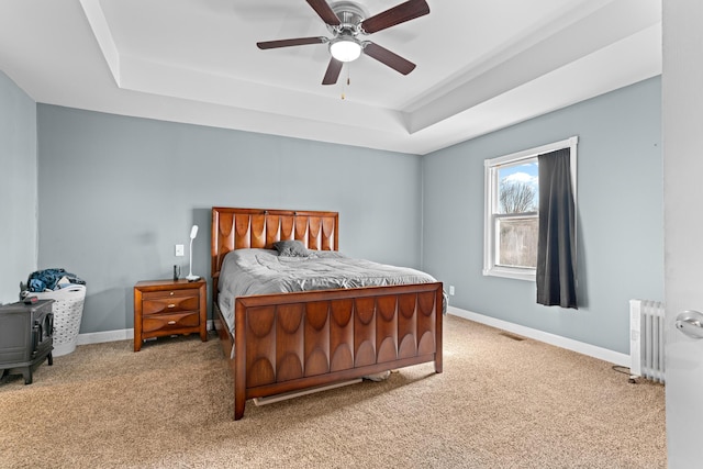 bedroom featuring ceiling fan, light colored carpet, radiator, and a raised ceiling