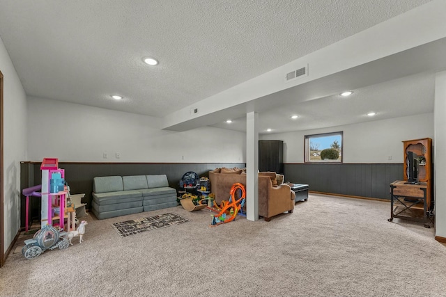 game room with carpet, a textured ceiling, and wooden walls