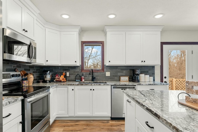 kitchen with sink, backsplash, white cabinets, and stainless steel appliances