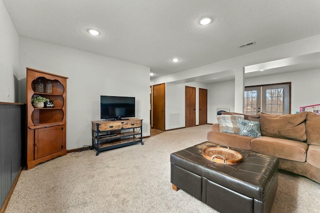 carpeted living room with a textured ceiling and french doors