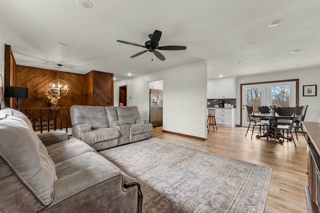 living room featuring light hardwood / wood-style floors and ceiling fan with notable chandelier