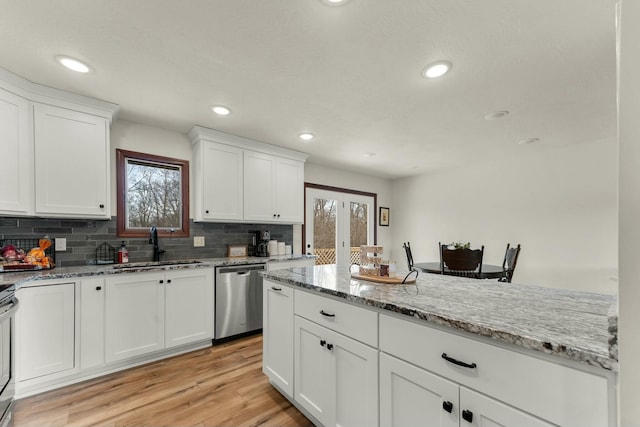 kitchen with light stone countertops, stainless steel dishwasher, white cabinets, sink, and a healthy amount of sunlight