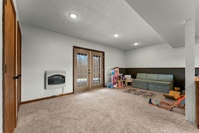 recreation room with a textured ceiling, carpet floors, heating unit, and french doors