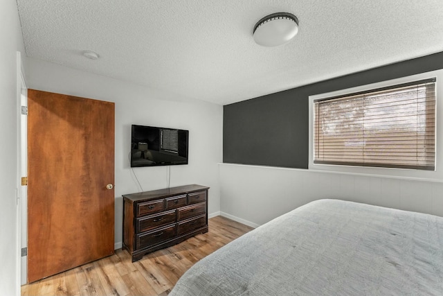 bedroom with light wood-type flooring and a textured ceiling