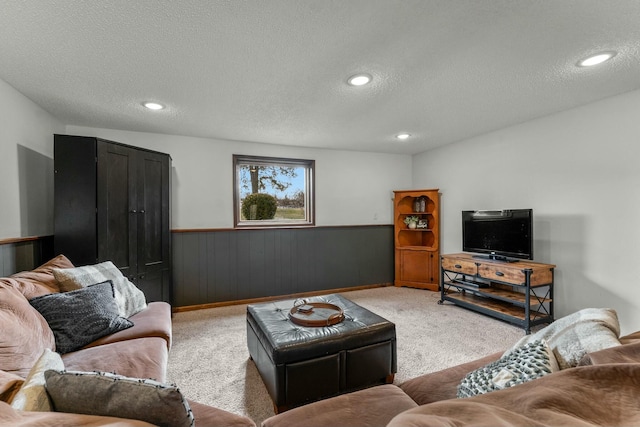 living room with wood walls, a textured ceiling, and light carpet