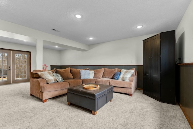 carpeted living room featuring a textured ceiling, french doors, and wooden walls