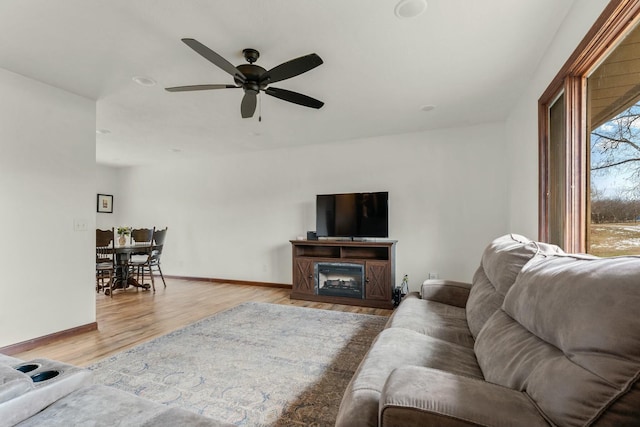 living room featuring light wood-type flooring, ceiling fan, and a fireplace