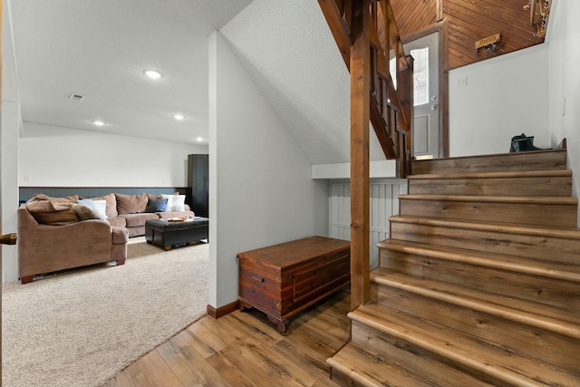 stairs featuring wood-type flooring and vaulted ceiling