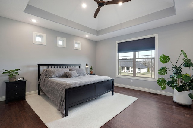 bedroom featuring dark wood-type flooring, ceiling fan, and a raised ceiling