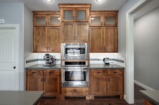 kitchen featuring decorative backsplash, a textured ceiling, dark hardwood / wood-style flooring, and stainless steel appliances