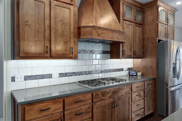 kitchen featuring decorative backsplash, stainless steel appliances, and custom range hood