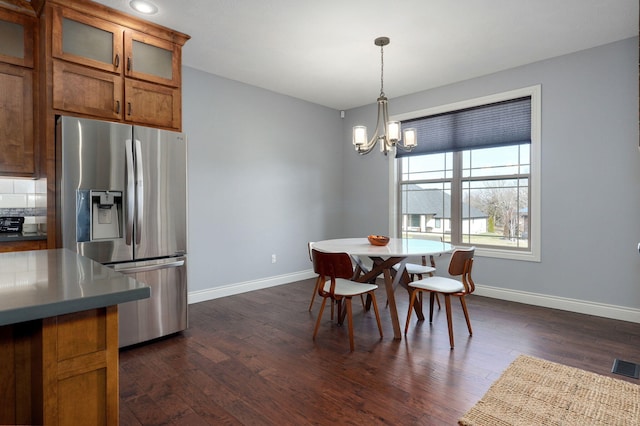 dining area with dark wood-type flooring and an inviting chandelier