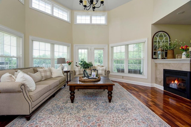 living room with hardwood / wood-style flooring, a high ceiling, an inviting chandelier, and a fireplace