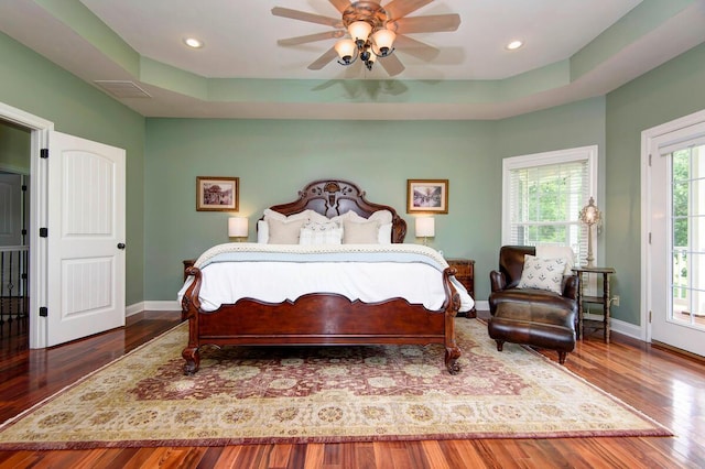 bedroom featuring a tray ceiling, access to outside, ceiling fan, and hardwood / wood-style flooring