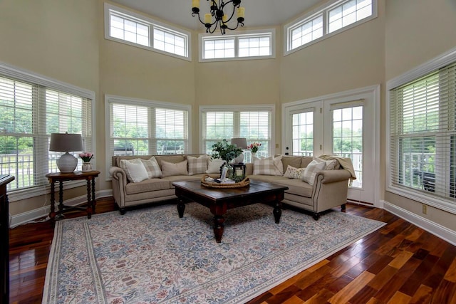 living room with dark wood-type flooring, plenty of natural light, a chandelier, and a high ceiling