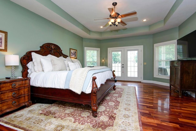 bedroom with french doors, wood-type flooring, access to outside, a tray ceiling, and ceiling fan