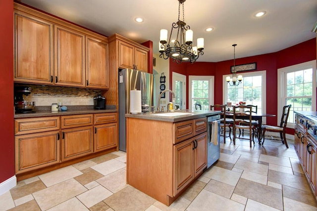 kitchen featuring sink, hanging light fixtures, stainless steel appliances, a notable chandelier, and a center island with sink