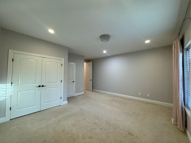 unfurnished bedroom with light colored carpet and a closet