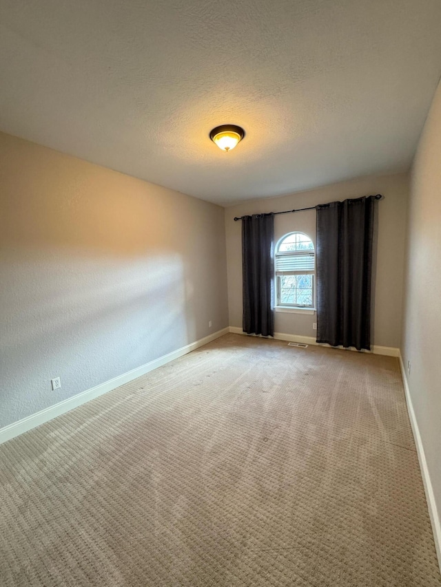 spare room featuring carpet flooring and a textured ceiling