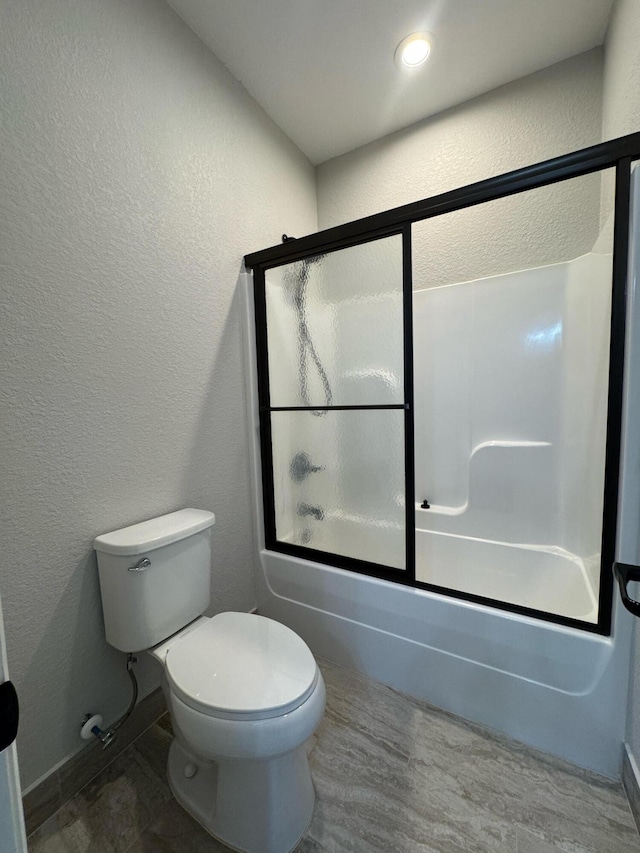 bathroom featuring combined bath / shower with glass door and toilet