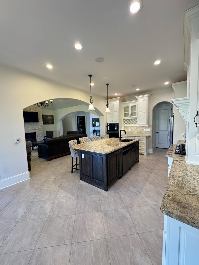 kitchen with white cabinets, dark brown cabinetry, sink, hanging light fixtures, and a kitchen island with sink