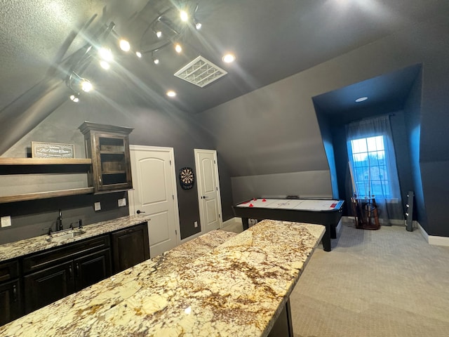 kitchen featuring light stone countertops, sink, lofted ceiling, and a kitchen island